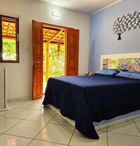 Un dormitorio con una cama azul y una puerta en Villa Mar a Vista - Suite Alamanda, en Cumuruxatiba