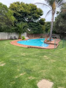 a swimming pool in a yard with a palm tree at Hillsview, Roodepoort in Roodepoort