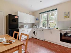 a kitchen with white cabinets and a table with a plate of food at 2 Bed in Glossop 52409 in Glossop