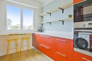 a kitchen with orange cabinets and two bar stools at T3 design et familial avec parking Biarritz proche commodités in Biarritz