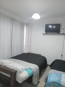 um quarto com duas camas e uma televisão na parede em M L em Navarro