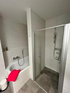 La salle de bains est pourvue d'une douche, d'une baignoire et d'une serviette rouge. dans l'établissement Luxembourg 2 bedroom apartment in Gasperich, à Luxembourg