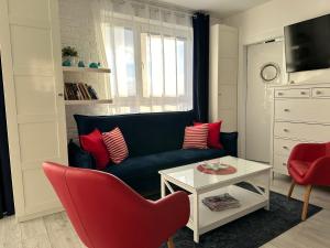 Amko Style Apartamenty Przystań 26 Willa Nord في ياستراوبيا جورا: غرفة معيشة مع أريكة سوداء وكراسي حمراء