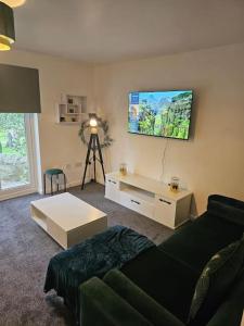 a living room with a couch and a tv on the wall at Betjiman Retreat Relaxtion Awaits in Gateshead