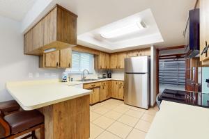 La cuisine est équipée d'armoires en bois et d'un réfrigérateur en acier inoxydable. dans l'établissement Flamingo Lane, à Cap Carnaveral