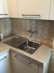 una cocina con fregadero de acero inoxidable y azulejos en Grazioso appartamento, en Cassina Valsassina