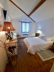 ein Schlafzimmer mit einem Bett und einem Tisch mit einer Lampe in der Unterkunft Pierres et Jardins in Senlis