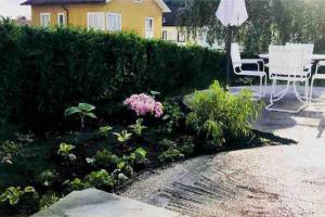 einen Garten mit einem Tisch, Stühlen und Pflanzen in der Unterkunft Eget hus i Örgryte. Göteborgs bästa läge! in Göteborg