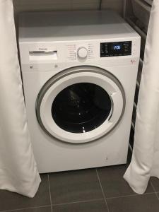 uma máquina de lavar roupa branca numa cozinha com cortinas em Eget hus i Örgryte. Göteborgs bästa läge! em Gotemburgo