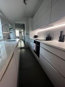 uma cozinha com armários brancos, um lavatório e um fogão em Regatta-Ready Escape em Henley on Thames