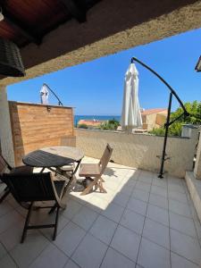 un patio con mesa, sillas y sombrilla en RESIDENCE LA PLAGE Pieds dans l'eau Belle Vue mer, en Linguizzetta