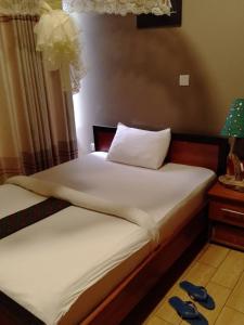 ein Schlafzimmer mit 2 Betten und einem Tisch mit einer Lampe in der Unterkunft Eric Hospitality Kigali BY KONGA in Kigali