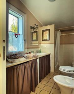 baño con lavabo y aseo y ventana en Un Giardino sul Lago, en Montefiascone