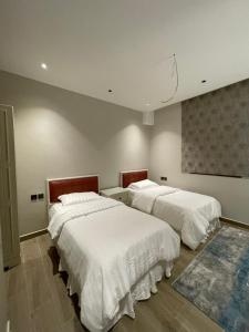 a bedroom with two beds with white sheets at شقة عائلية خاصة in Dhahran