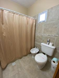 Un baño con inodoro y cortina de ducha. en Complejo "NONI" 200 mts del mar, barrio tranquilo, en Las Grutas