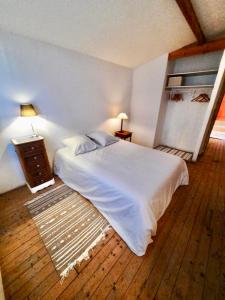 Schlafzimmer mit einem weißen Bett und Holzboden in der Unterkunft Pierres et Jardins in Senlis