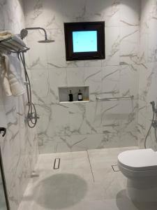 ein Bad mit WC und ein TV an der Wand in der Unterkunft شقة عائلية خاصة in Dhahran