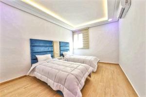 sypialnia z 2 łóżkami i niebieskim zagłówkiem w obiekcie Cosy Apartment 2 Bedrooms Golf City w Marakeszu