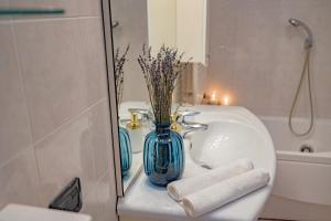 um lavatório de casa de banho com um vaso azul e toalhas em Porta Romana Suite di Charme em Milão