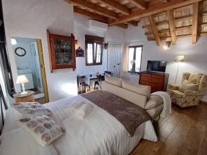 a bedroom with a large bed and a living room at La Guarida de Vejer Casa Rural in Vejer de la Frontera
