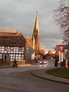 a church with a steeple and a car driving down a street at Wellcome in Evita House in Dassel