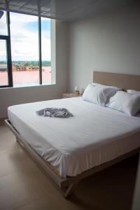1 cama blanca en un dormitorio con ventana grande en Hotel Amazonas Suite, Suite Presidencial en Nueva Loja