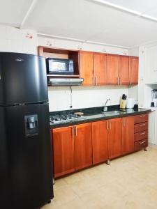 uma cozinha com um frigorífico preto e armários de madeira em Apartamento Estadio Laureles em Medellín
