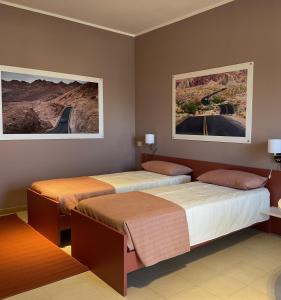 duas camas num quarto com dois cartazes na parede em Motel Vespucci em Guasticce