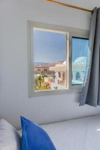 een slaapkamer met een raam met uitzicht op de stad bij Al Deira Dahab Hotel in Dahab