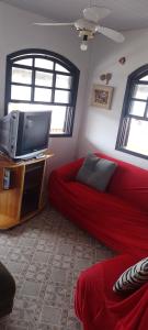 Una sala de estar con un sofá rojo y un televisor de pantalla plana. en Solar Dona Irma, en Guaratuba