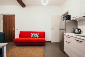 un sofá rojo en una cocina con nevera en Bigattera bilocali - Affitti Brevi Italia, en Varese