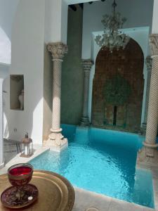 una gran piscina con columnas y una lámpara de araña en Riad Khalifa, en Marrakech