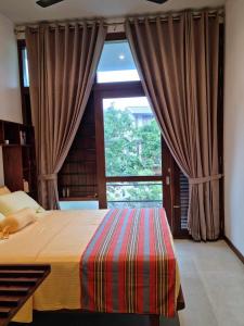 a bedroom with a bed and a large window at Still Waters - A Cottage by the Lake! in Boralesgamuwa