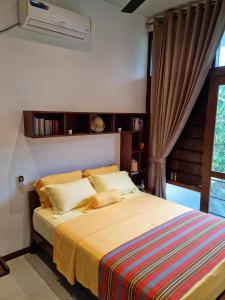 a bedroom with a bed and a window with a fan at Still Waters - A Cottage by the Lake! in Boralesgamuwa +55 photos