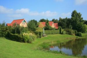 una casa con techos rojos junto a un río en Summio Villapark Akenveen en Tynaarlo