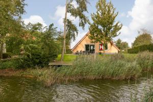 a house next to a river with grass at Summio Villapark Akenveen in Tynaarlo