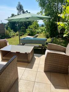 einen Tisch, Stühle und einen Regenschirm auf einer Terrasse in der Unterkunft un ecrin de verdure face à la mer in Isolaccio-di-Fiumorbo