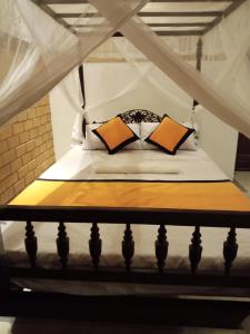 Una cama con sábanas blancas y almohadas naranjas. en The Brick Wonder, en Habaraduwa Central