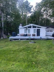 ein kleines weißes Haus in einem Hof mit einem Grasfeld in der Unterkunft Luxury Poconos Home Near Skiing, Lakes, & Waterparks in Tobyhanna