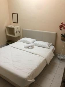 a large white bed with white sheets and pillows at Azaliza Homestay in Ayer Keroh