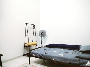a bedroom with a bed and a fan and a chair at Ummi Homestay Bukit Katil Melaka in Kampong Bukit Katil