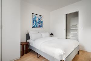 a white bedroom with a white bed and a painting at Residence Clichy - Dagobert in Clichy