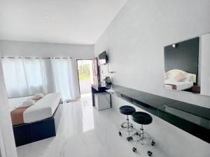 a bedroom with a bed and a mirror and two stools at BM Beach Resort Satun บีเอ็มบีชรีสอร์ท in Ban Pak Ba Ra