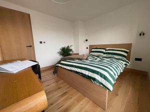 ein Schlafzimmer mit einem Bett mit einer grün und weiß gestreiften Decke in der Unterkunft Contemporary Detached Eco House in Ore