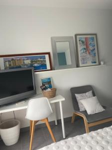 een woonkamer met een tv en een stoel bij Ama Lur in Hasparren