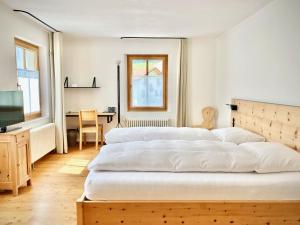 een slaapkamer met 2 bedden, een bureau en een televisie bij Hotel Central La Fainera Superior in Valchava