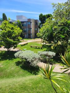 um parque com bancos e árvores em frente a um edifício em Apartamento Iloa residence na Barra de São Miguel