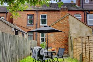 a table and chairs with an umbrella in a backyard at Cosy 3BR Gem, Sleeps 6, Near Town Centre in Coventry