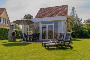 een patio met stoelen en een parasol op het gras bij Summio Vakantiepark Emslandermeer in Vlagtwedde