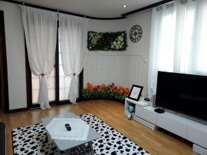 ein Wohnzimmer mit einem Flachbild-TV und einem Tisch in der Unterkunft Atti in Pyeongtaek
